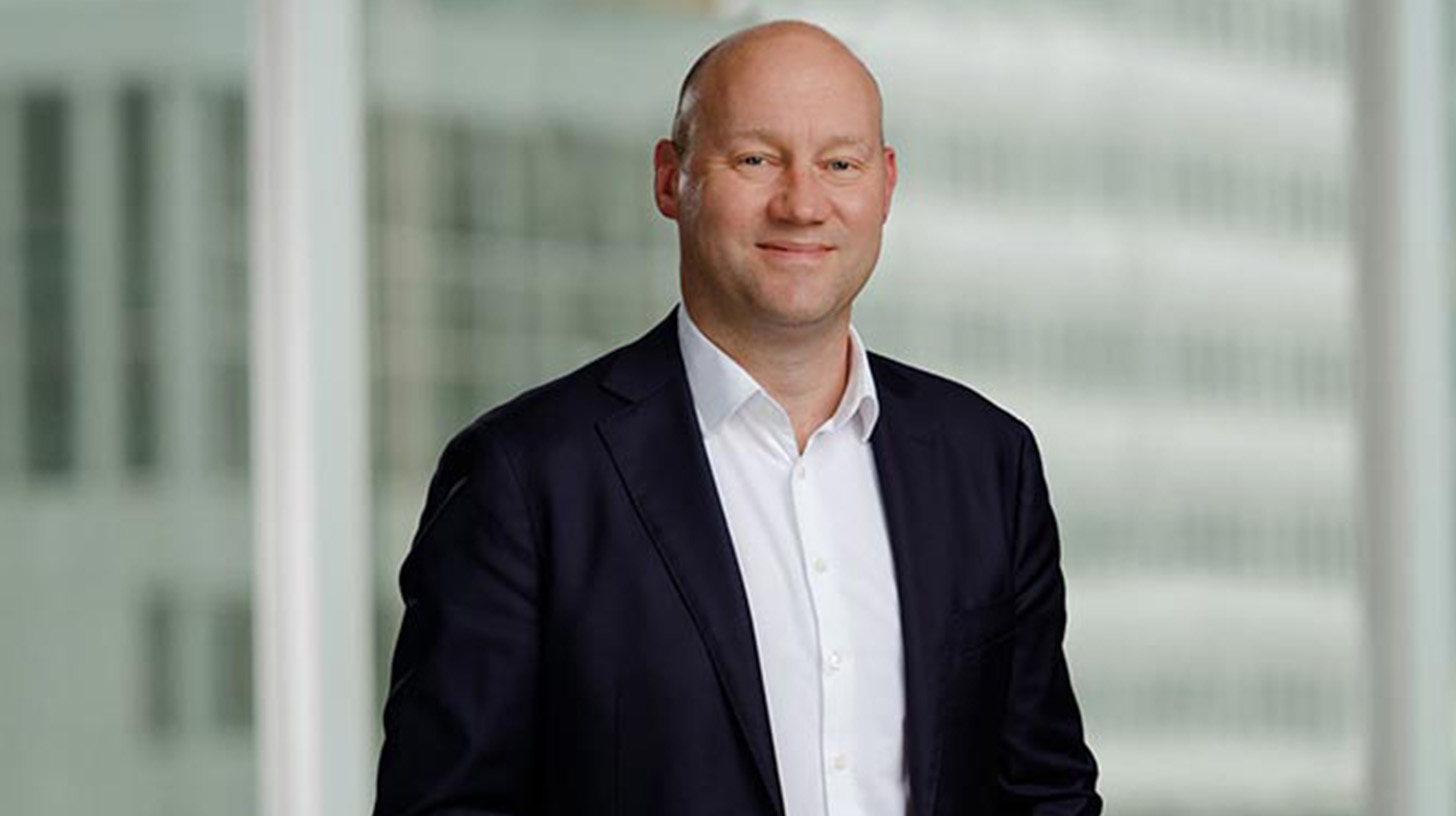 Porträtt av vit man i svart kostymjacka och vit skjorta